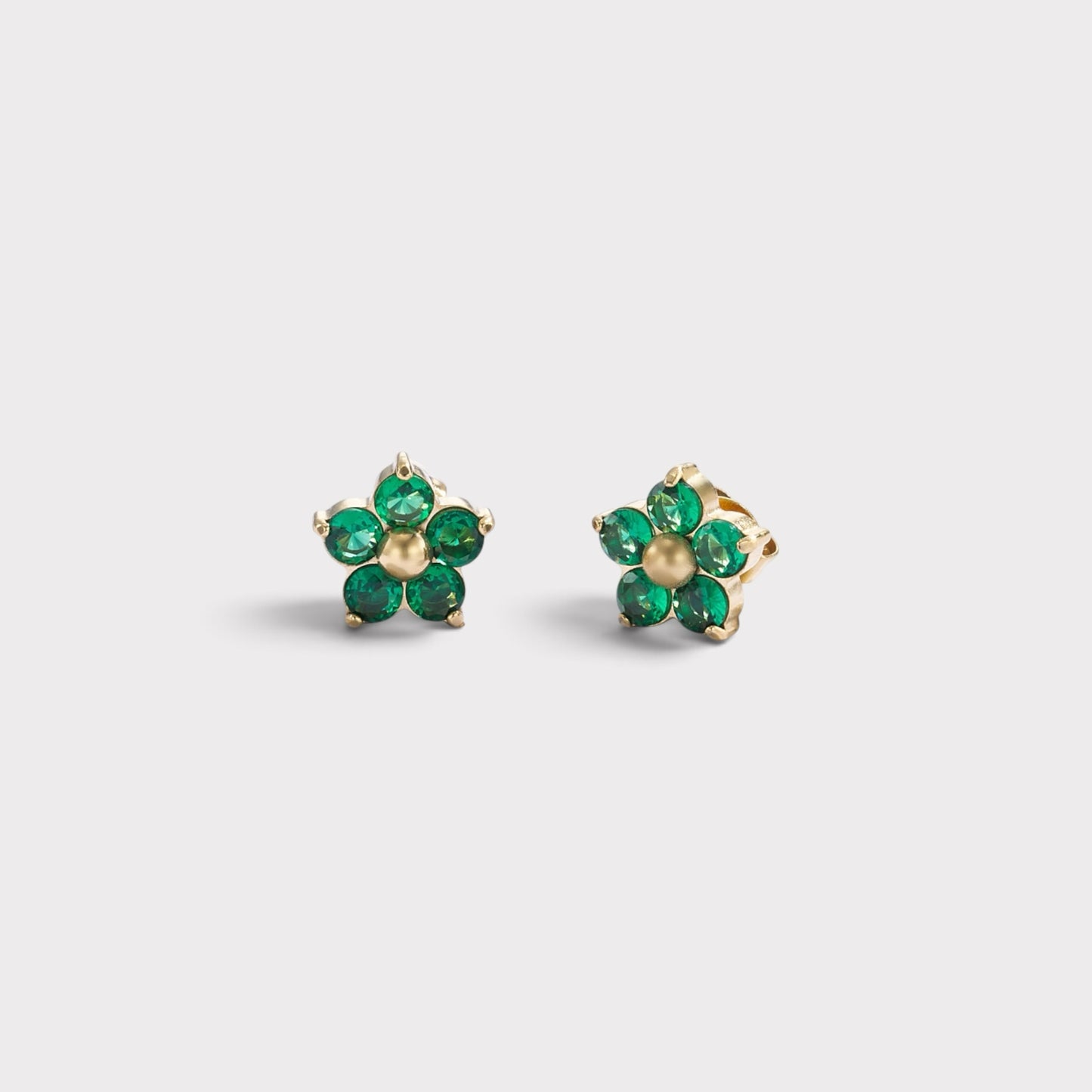 Brincos Verve em formato de flor com cristais verdes brilhantes e centro dourado, design delicado e elegante.
