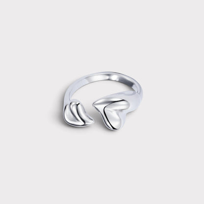 Anel Verve ajustável em metal prateado com design minimalista de dois corações estilizados e acabamento polido.