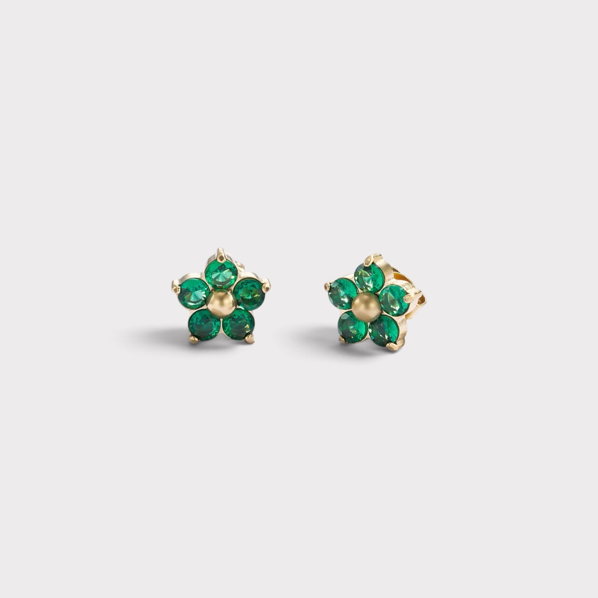 Brincos Verve em formato de flor com cristais verdes brilhantes e centro dourado, design delicado e elegante.